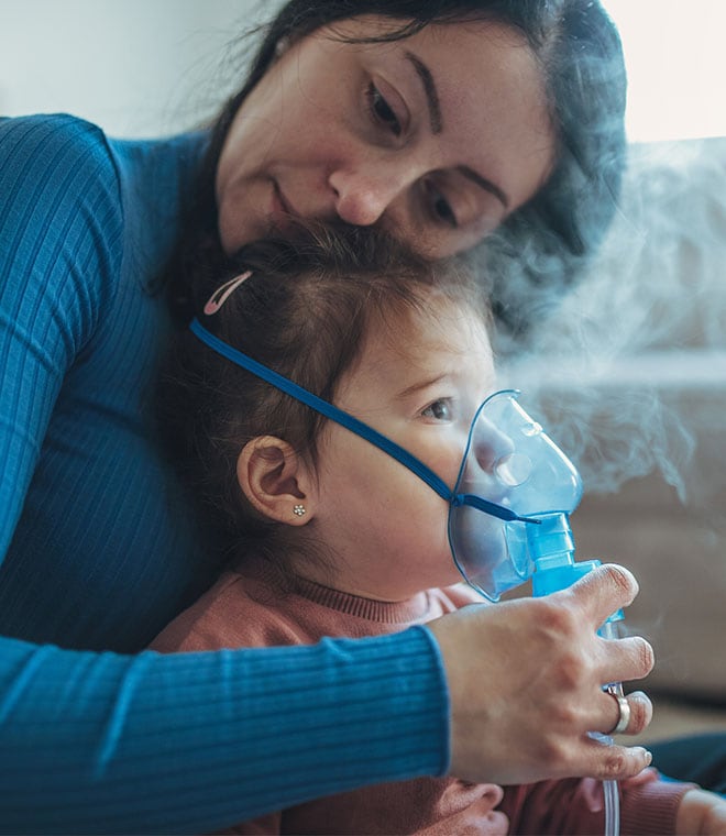 Mom holding her child and administering a breathing treatment