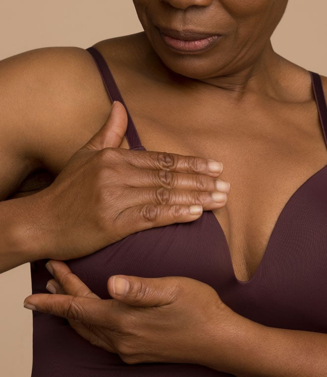 Middle aged black woman checking her breast for lumps