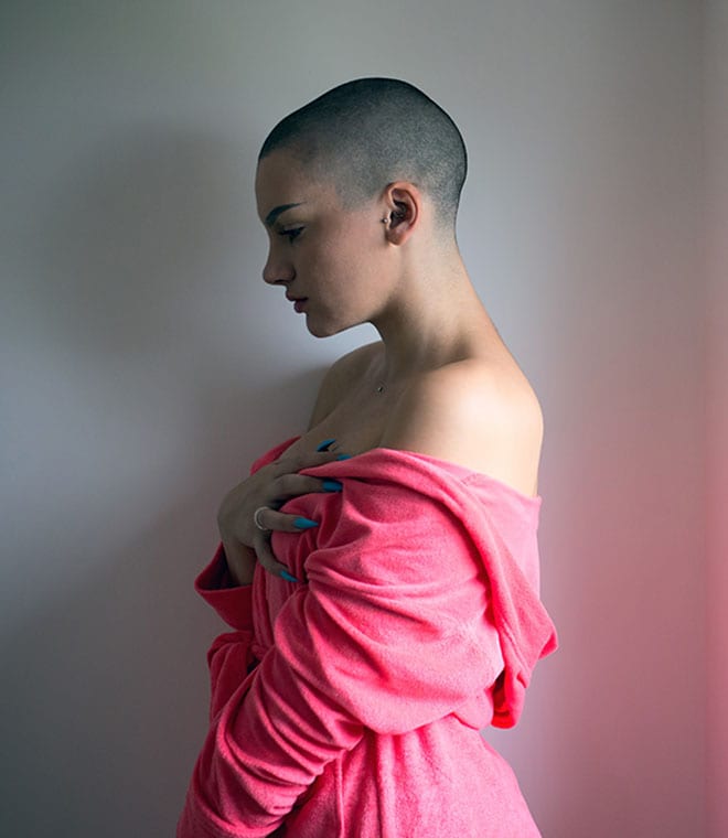 Young woman with shaved head holding her chest
