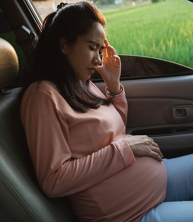 Woman in car holding her stomach
