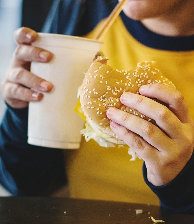 Person in yellow shirt eating a burger