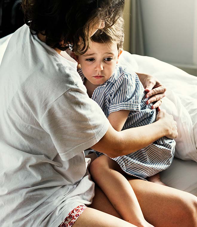 White mom comforting young boy in bed after a nightmare