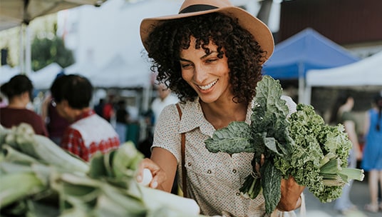 Woman smiling in a hat at the farmers market