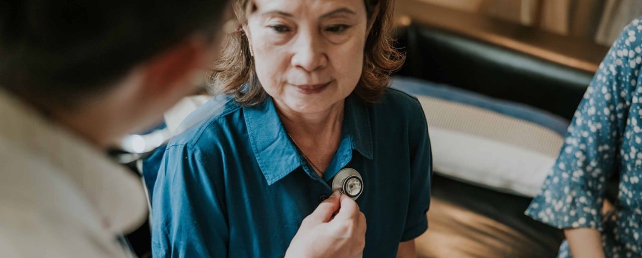 A doctor use stethoscope to examine an old lady