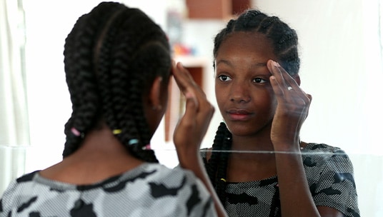Young black girl looking in the mirror