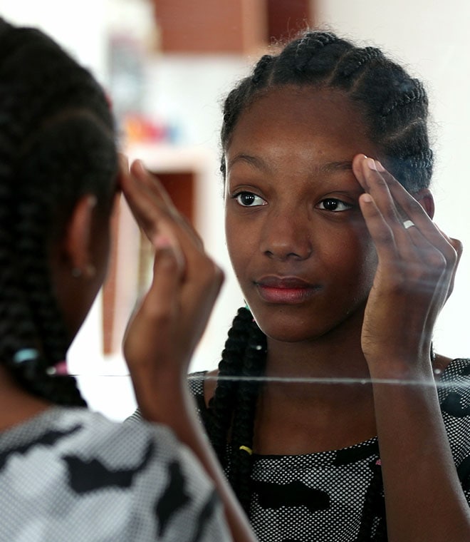 Young black girl looking at herself in the mirror