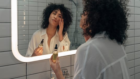 Woman applying serum in the mirror