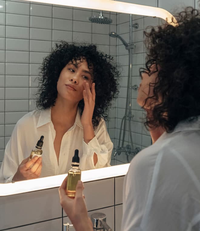 Millennial woman applying serums in the mirror