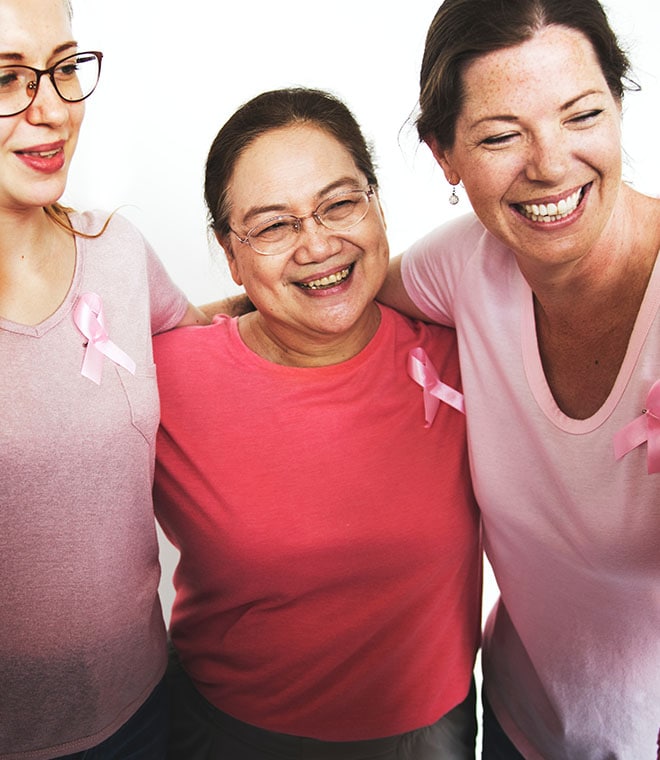 Women in pink shirts and ribbons smiling at the camera