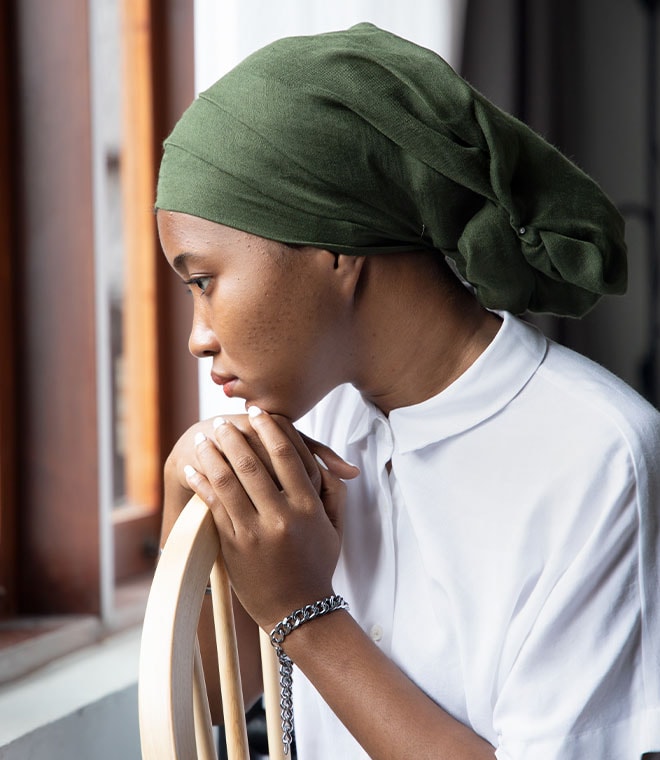 Black girl with a green headwrap sitting in a chair