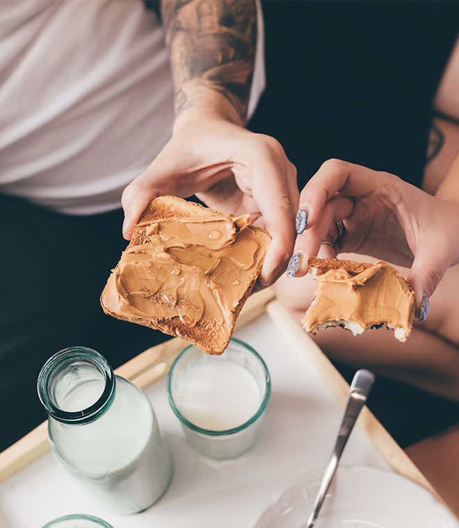 Two people holding peanut butter toast