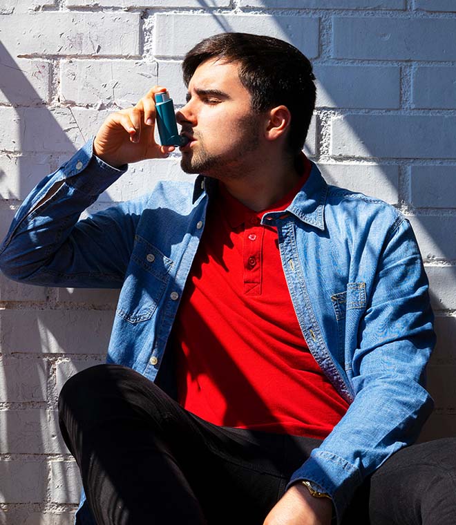 Man in a red shirt using an inhaler