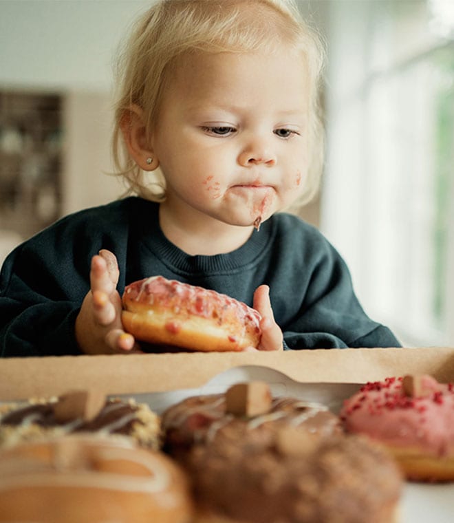 Blonde toddler eating donuts
