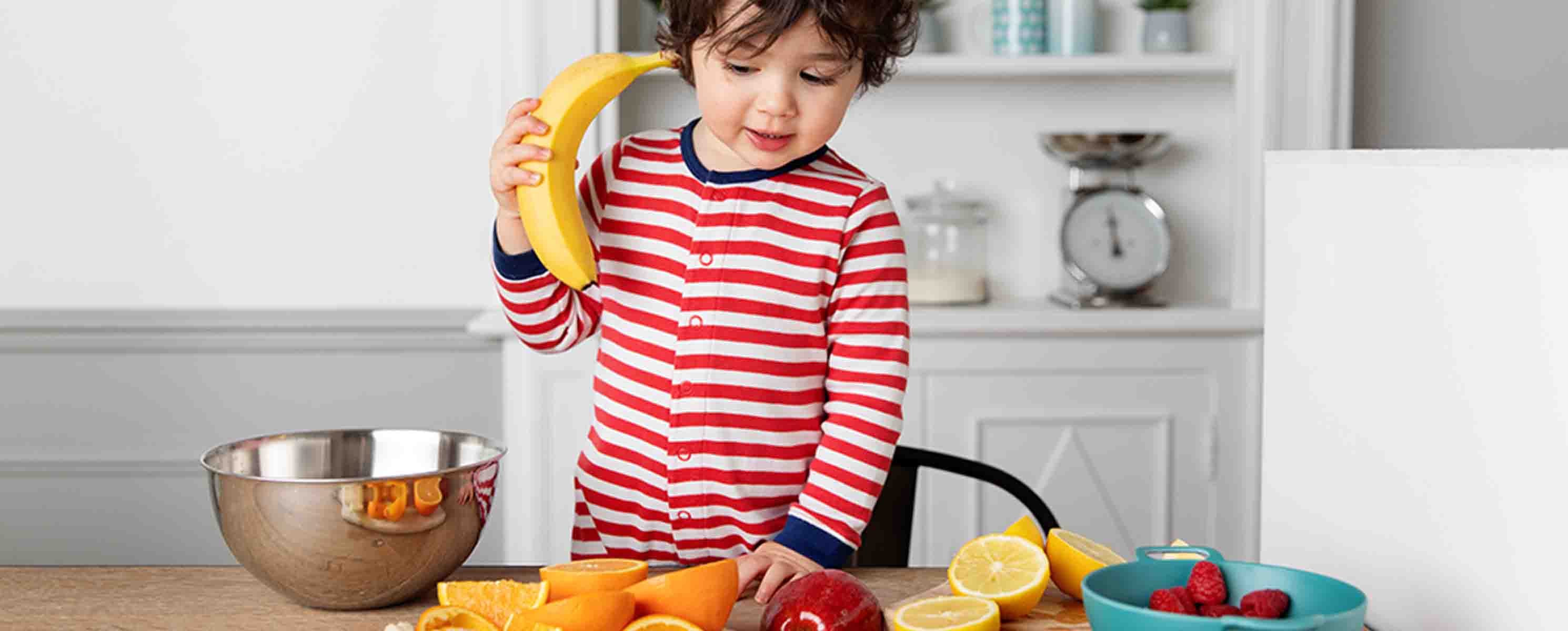 Toddler playing with fruit at a table