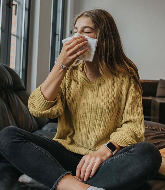 Younger white woman in yellow sweater wiping her nose