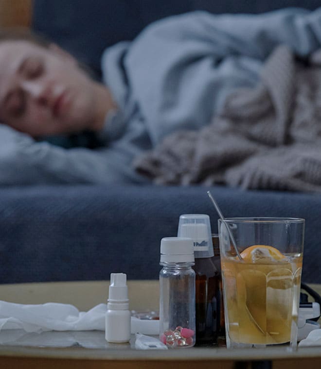 Woman sleeping on couch with medicine on coffee table
