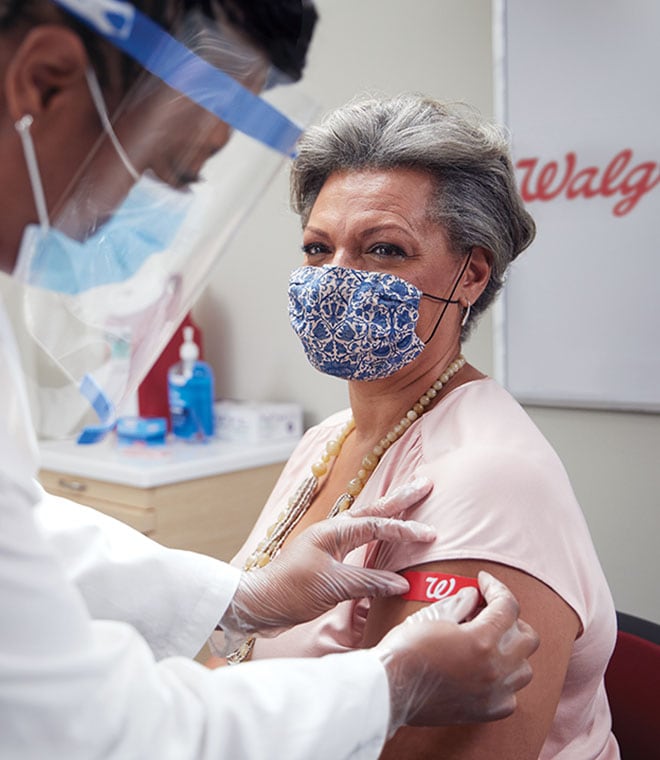 Older Spanish woman getting a Walgreens bandaid over a covid booster shot
