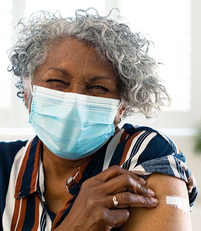 Older black woman in mask with band-aid on arm