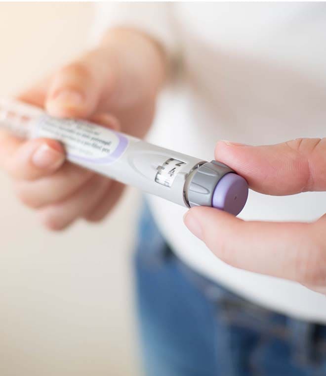 Person holding insulin pen with purple cap