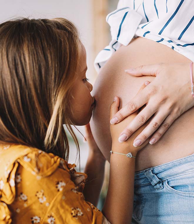 Girl kissing pregnant mom's belly