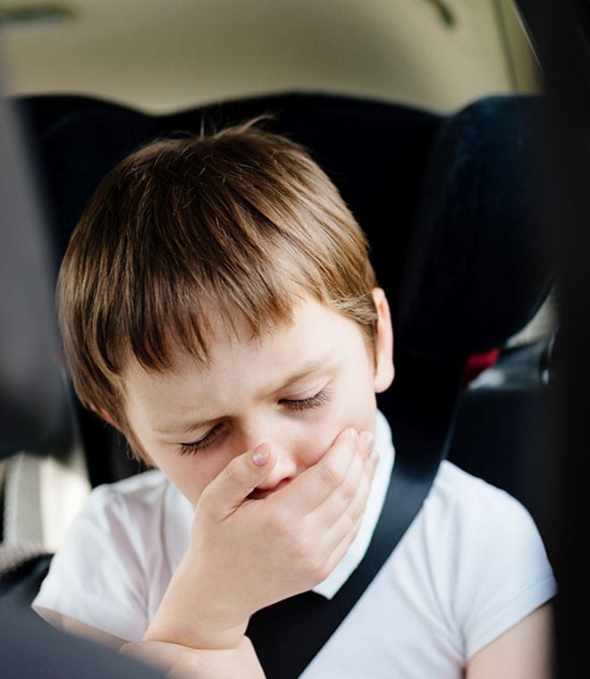 Young white boy in carseat covering his mouth