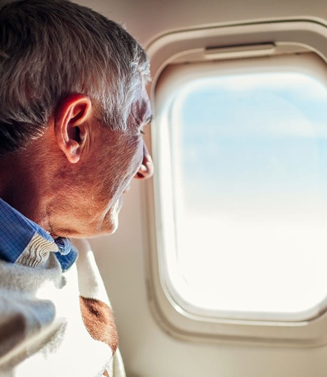 Older white man looking out airplane window