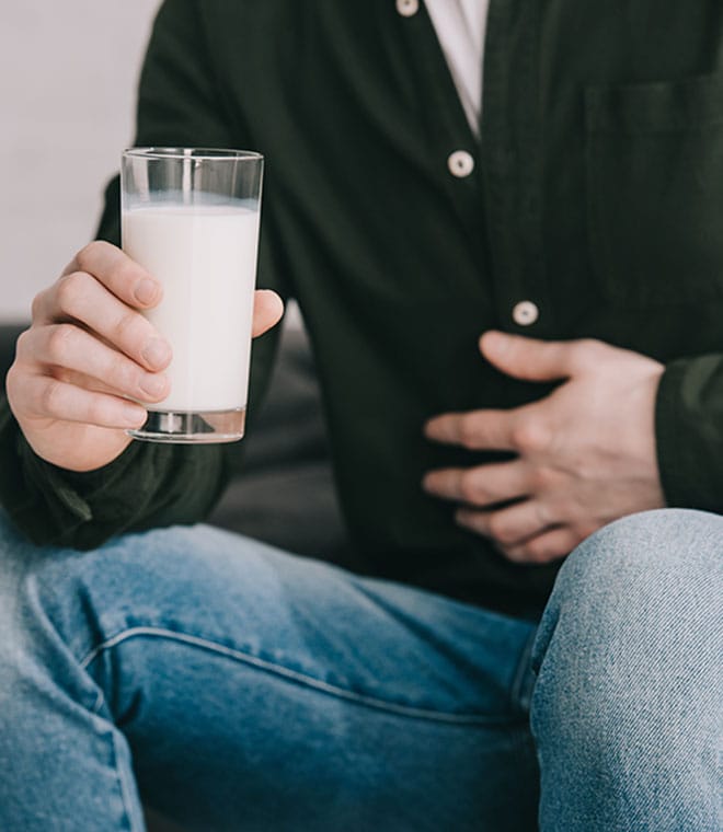 Man with glass of milk holding stomach