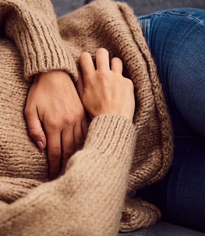 Woman in brown sweater holding her stomach