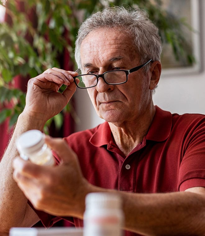 Older white man reading pill bottle