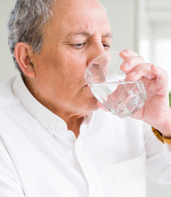 Older white man drinking a glass of water