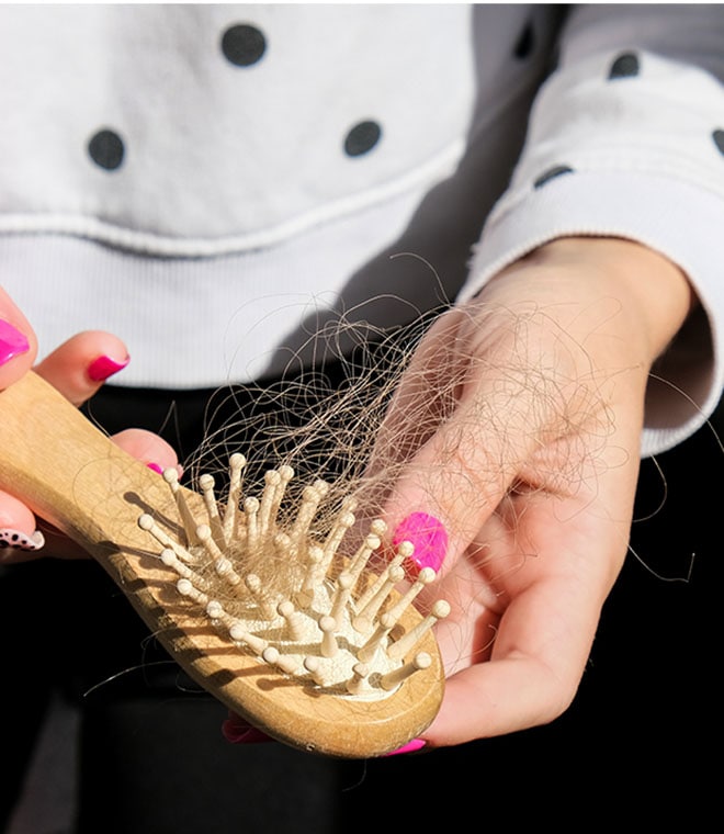White woman pulling hair out of a brush