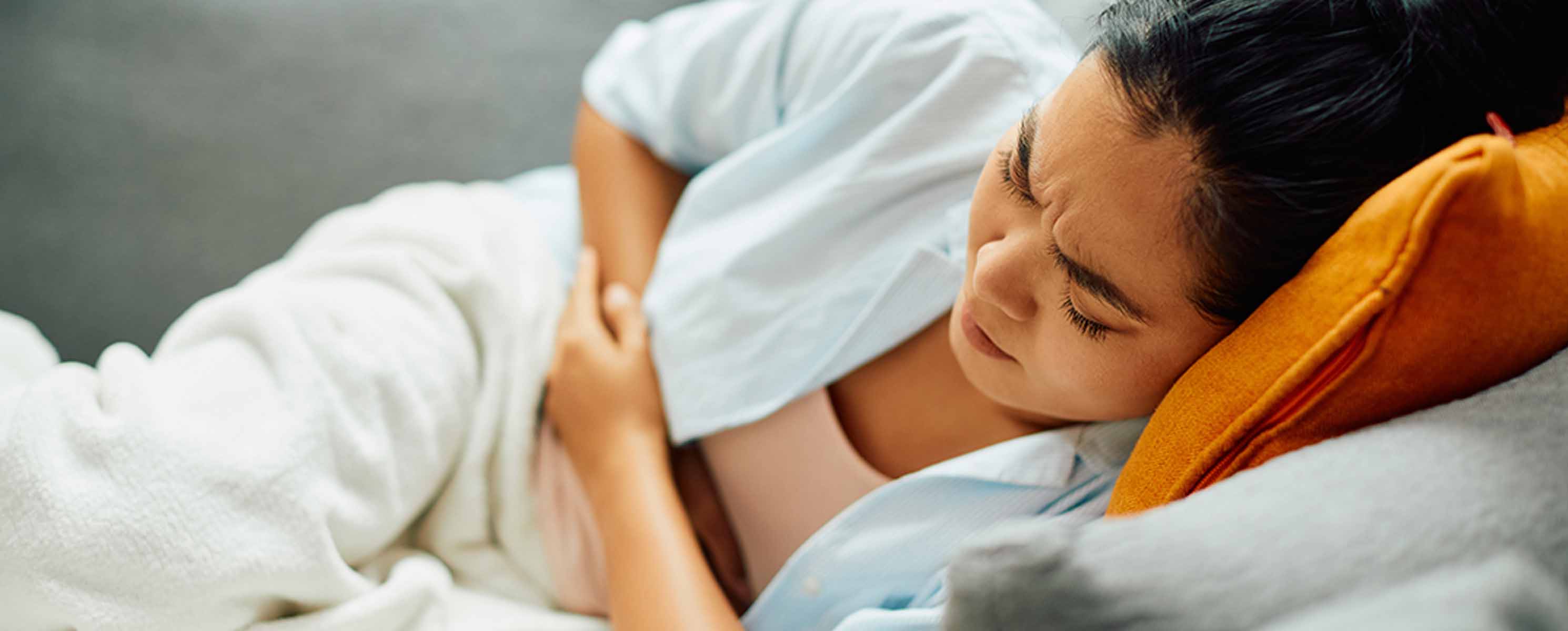 Woman laying on couch holding her stomach