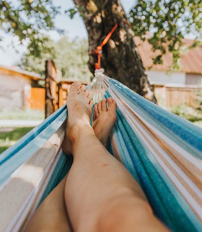 White person resting in a hammock with their feet propped