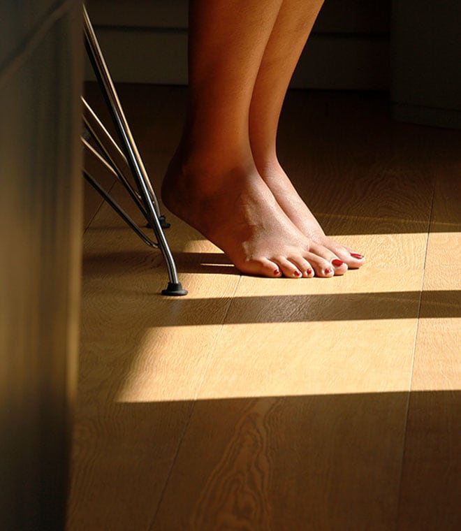 White feet with painted toenails on a wooden floor