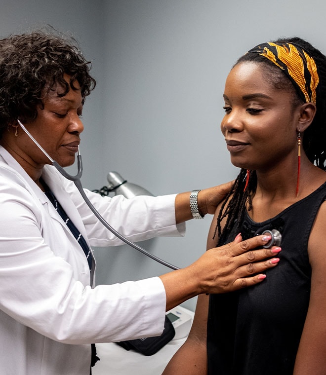 Black female doctor checking a young black woman's heart
