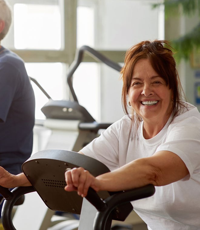 Woman riding an elliptical and smiling