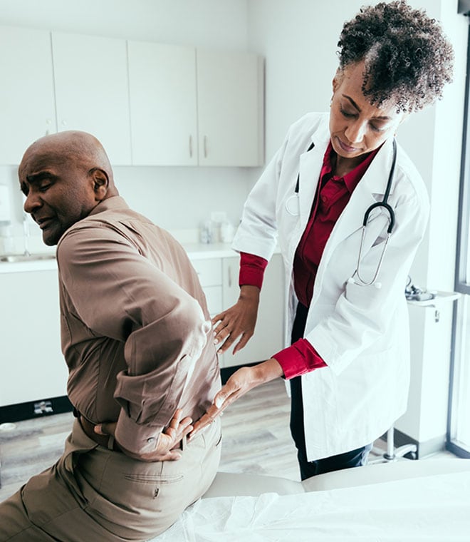 Black doctor in her 50s examining a patients back
