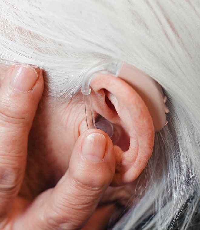 Older woman adjusting a hearing aid
