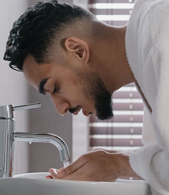 Millennial man washing his face
