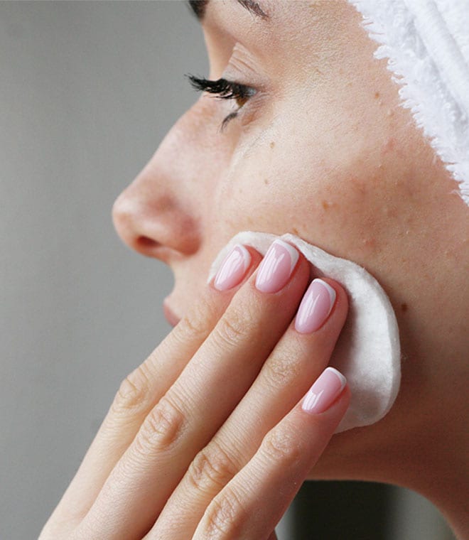 Young woman washing her face with cotton pad