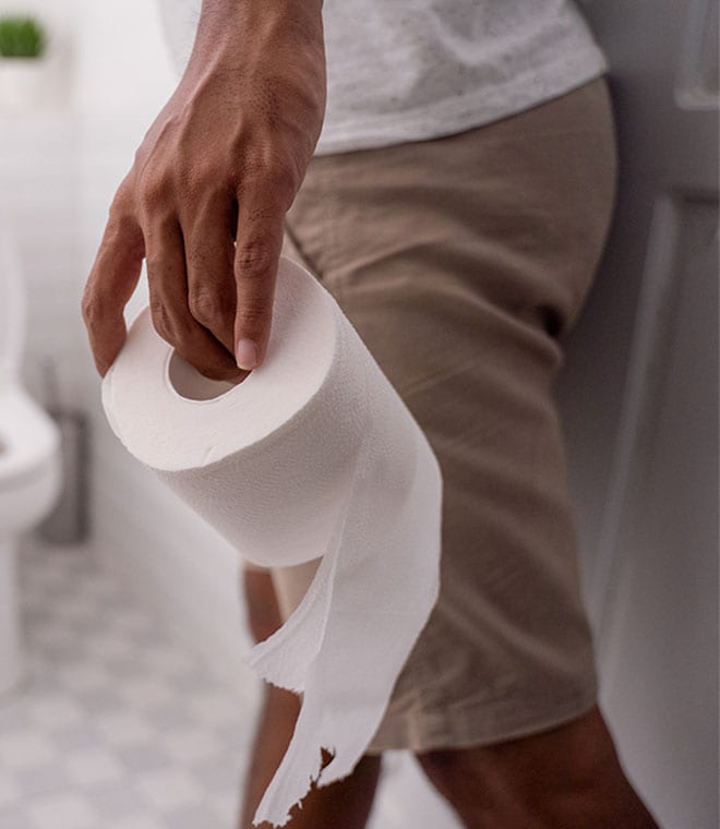 man going into a bathroom with toilet tissue in his hand