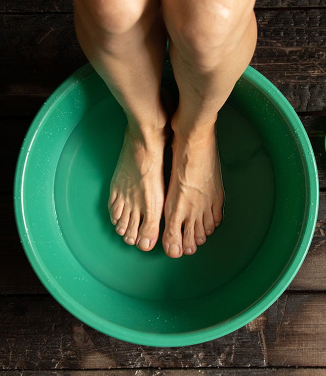 Woman soaking her feet in a green pail