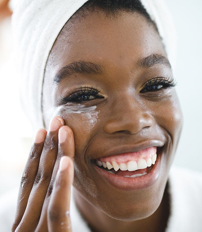 Young black woman applying moisturizer