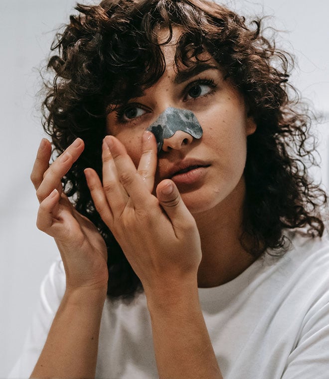 Woman with curly hair applying a nose strip