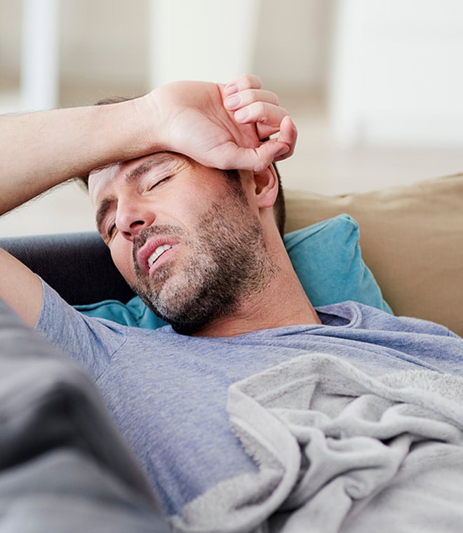 White man laying on couch with arm over forehead
