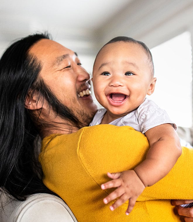 Asian dad and his infant son smiling and laughing