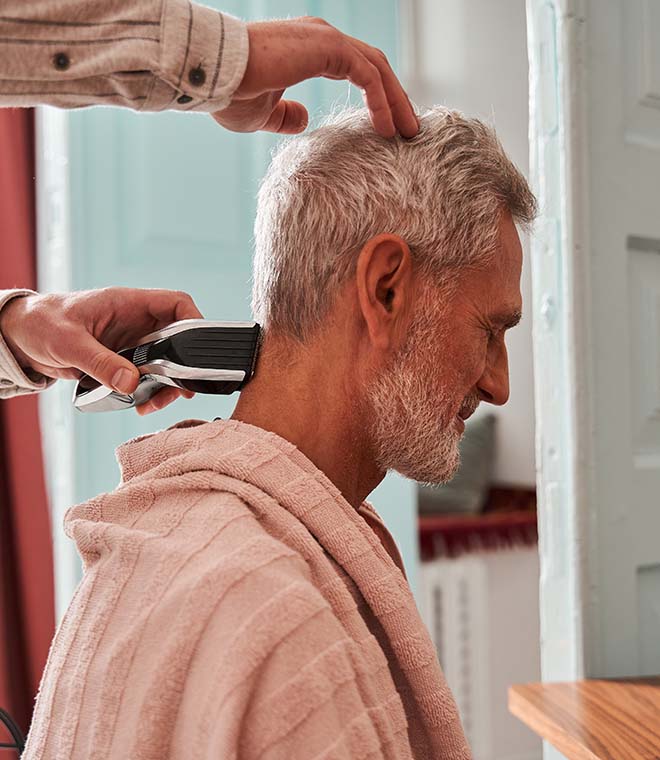 Caregiver cutting older man's hair