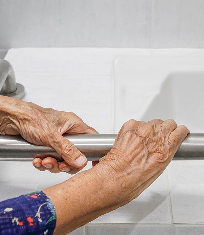 Older white woman holding bathroom safety rail