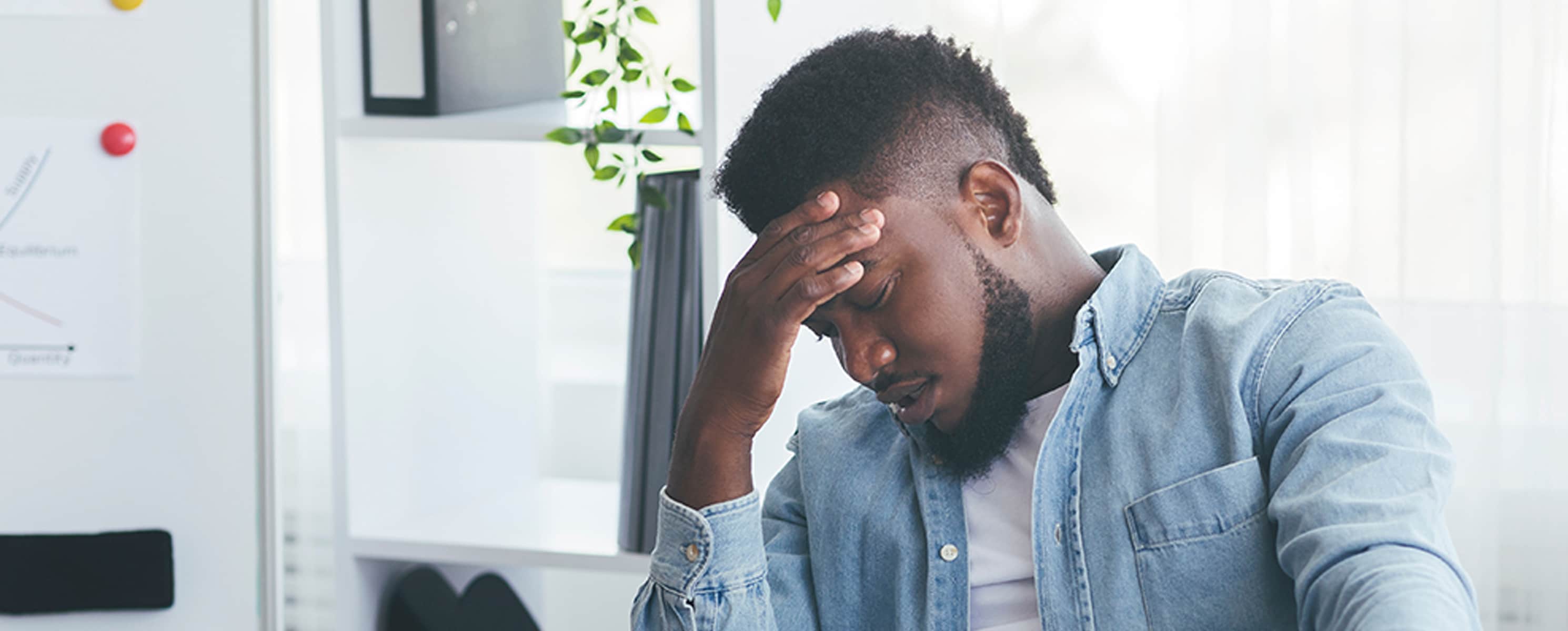 Young black man sitting with his head in his hand