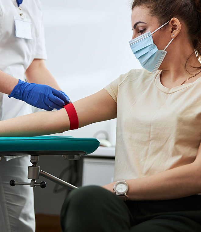Young woman with a mask having blood drawn